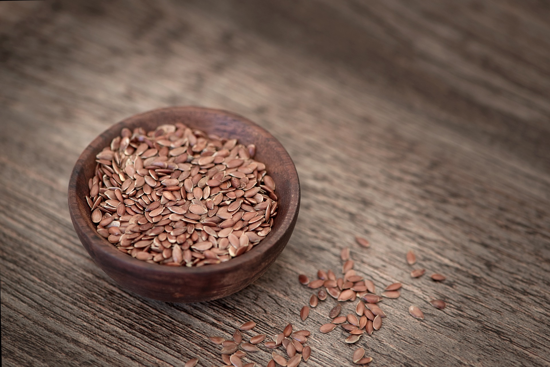 flax seeds in a wooden bowl on a wooden table