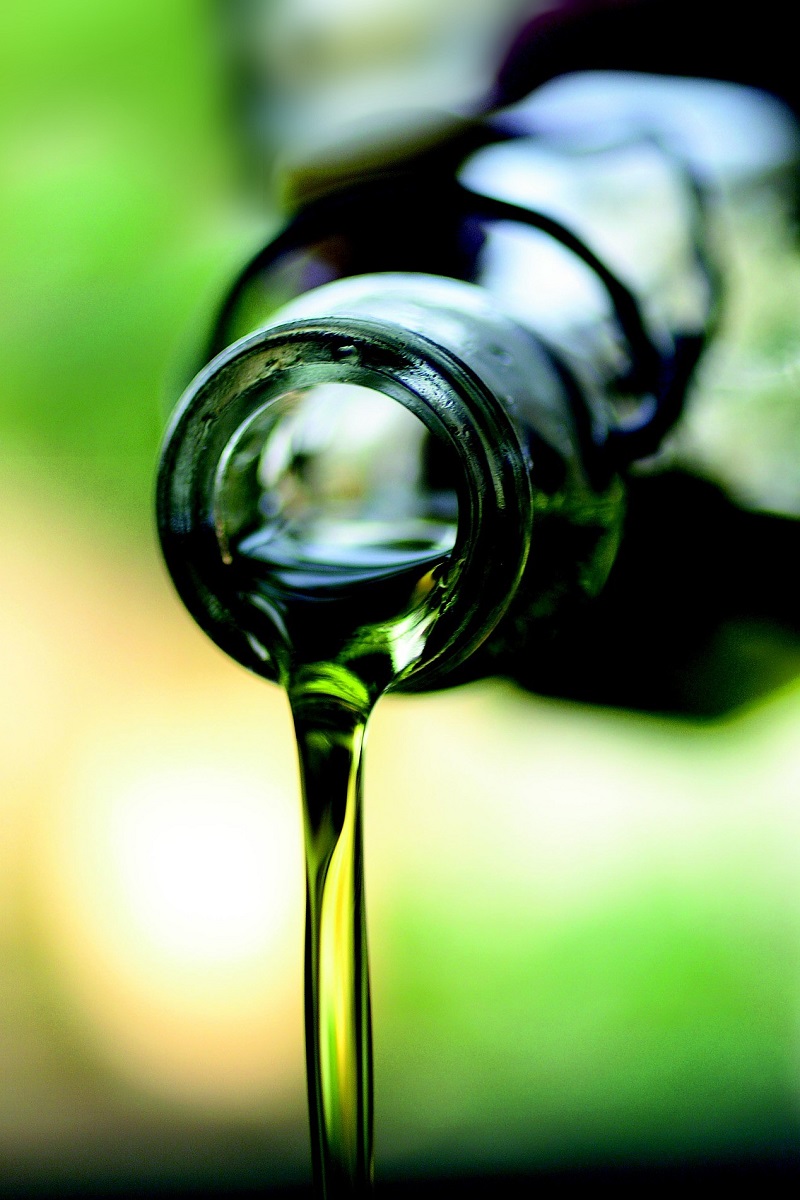 Olivenöl gegossen aus einer Glasflasche zum gesunden Backen und Braten