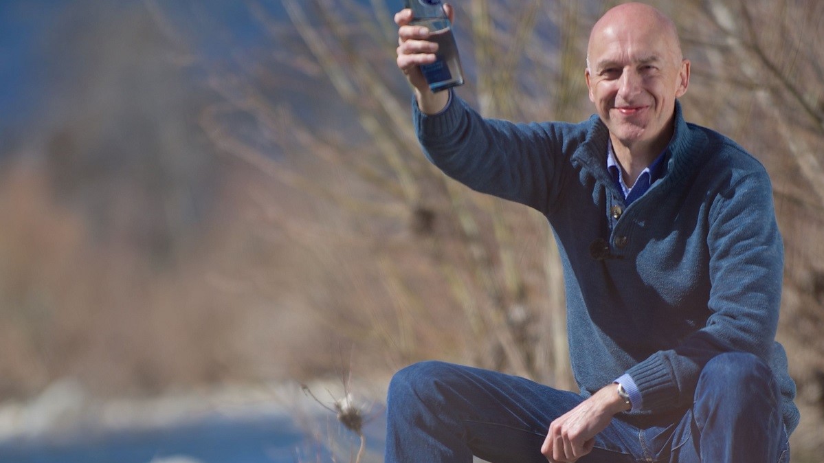 man met mineraal water in glazen fles in hand van man