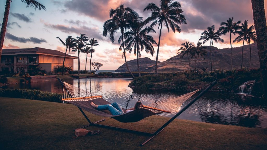 Wellness mit Kokosöl, entspannt in einer Hängematte liegen mit Aussicht über Meer und Palmen