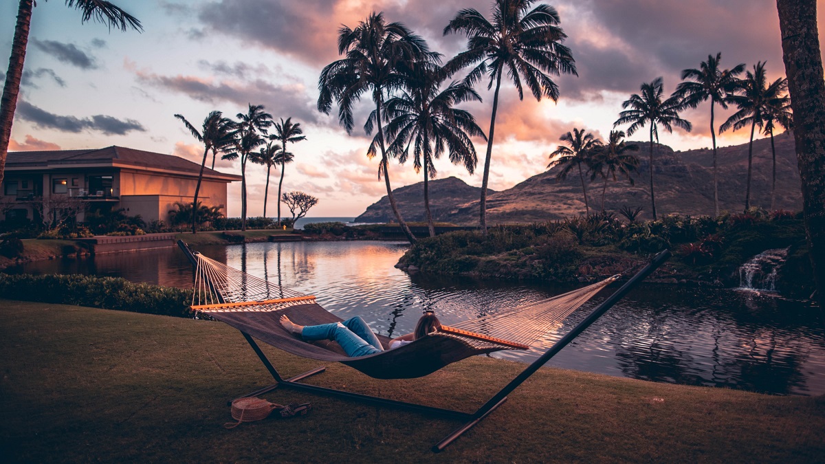 wellness met kokosolie ontspannen liggen in een hangmat met uitzicht over water en palmbomen