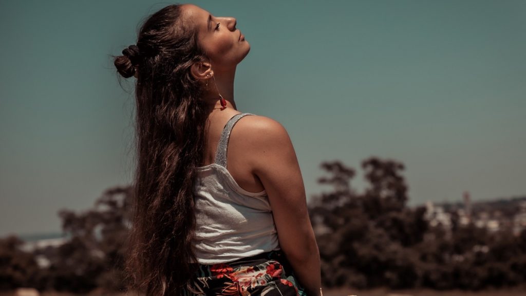 woman enjoys the sun and moisturises with coconut oil at home