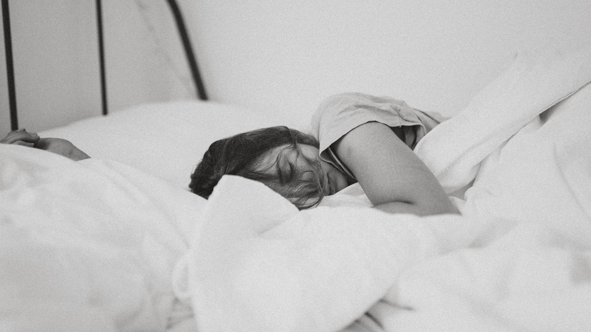 Une femme tranquillement en train de dormir dans un lit grâce à l'huile de coco