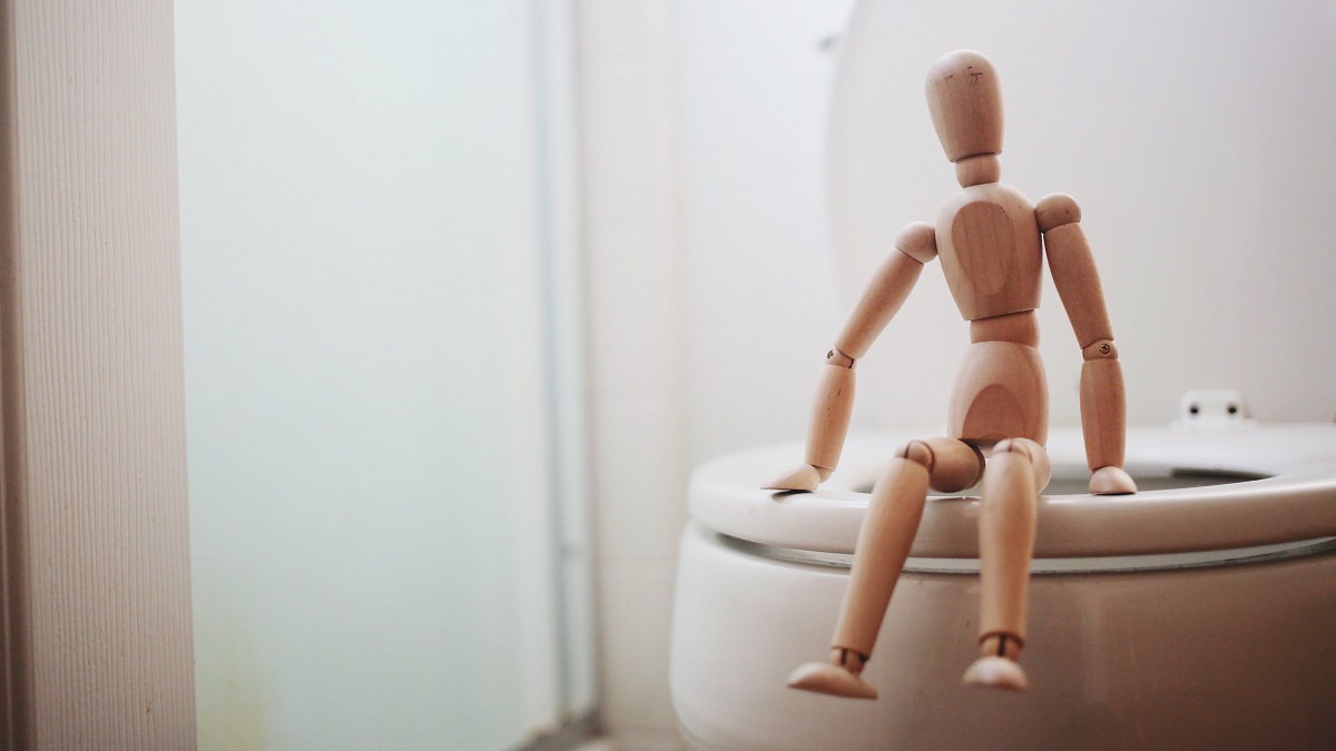 wooden doll on toilet coconut oil helps against constipation